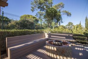 a garden bench with a barrel in the shade at Villa Joy in Olhos de Água