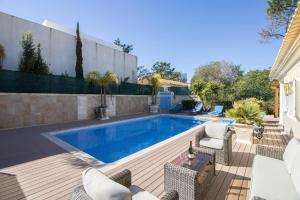 a swimming pool in a backyard with chairs and a table at Villa Joy in Olhos de Água