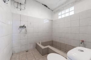 a bathroom with a toilet and a bath tub at Urbanview Hotel D'Pineapple Villa Ciater by RedDoorz in Subang +52 photos