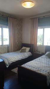 two beds in a room with two windows at Quattro Sea View Beachfront Ap 6 in Larnaka