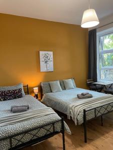1 dormitorio con 2 camas y ventana en Contemporary Private ROOMS Near Central London, en Londres