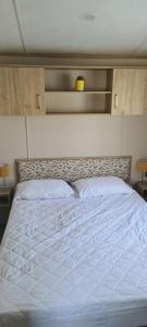 uma cama grande num quarto com uma colcha branca em Ashdale By Sea em Whitstable