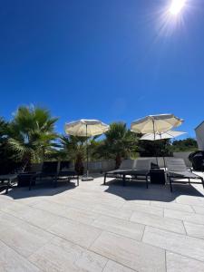 eine Gruppe von Bänken und Sonnenschirmen auf einer Terrasse in der Unterkunft Holiday Luxury Resort Sundance in Trogir