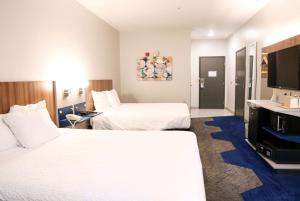 a hotel room with two beds and a flat screen tv at Microtel Inn & Suites by Wyndham Charlotte/Northlake in Charlotte