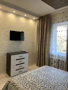 1 dormitorio con 1 cama, vestidor y TV en Кылышбай акына en Taraz