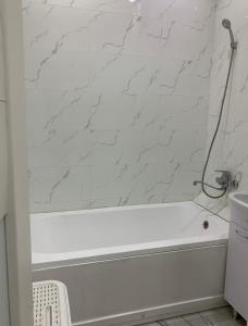 eine weiße Badewanne im Bad mit Marmorwand in der Unterkunft Кылышбай акына in Taras