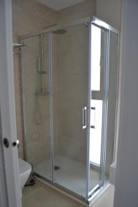 a shower with a glass door in a bathroom at Hotel OASIS CENTRO in Conil de la Frontera