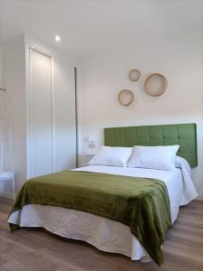 een slaapkamer met een groot bed met een groen hoofdeinde bij Pensión Os Mollados in O Pedrouzo