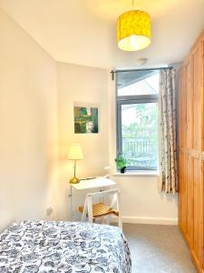 a bedroom with a bed and a desk and a window at Modern Patio Flat close to Sation & Canary Wharf in London
