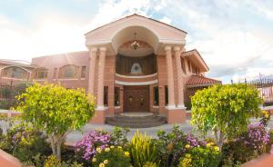 un grand bâtiment rose avec une fontaine devant lui dans l'établissement Hotel Spa Casa Real, à Riobamba
