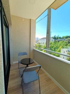 einen Balkon mit 2 Stühlen, einem Tisch und einem Fenster in der Unterkunft Pensión Os Mollados in O Pedrouzo