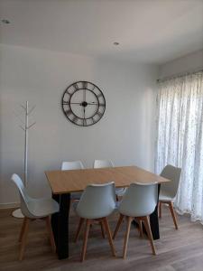 a dining room table with chairs and a clock on the wall at Pensión Os Mollados in O Pedrouzo