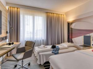 een hotelkamer met 2 bedden en een bureau bij Novotel Köln City in Keulen