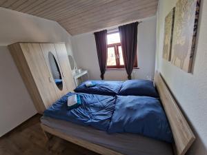 una camera da letto con un letto con lenzuola blu e una finestra di 98qm Wohnung im Villenviertel - Voll ausgestattet mit Balkon und Kamin - WLAN gratis a Wilhelmshaven