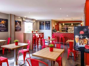 un restaurant avec des chaises et des tables rouges ainsi qu'un bar dans l'établissement Ibis Madrid Alcorcon Tresaguas, à Alcorcón