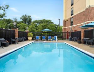 a swimming pool with chairs and tables and a building at Hampton Inn & Suites Arundel Mills/Baltimore in Hanover