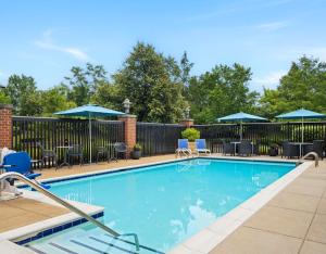 a swimming pool with chairs and umbrellas at Hampton Inn & Suites Arundel Mills/Baltimore in Hanover