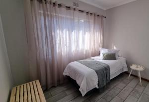 金伯利11 Debonair Self Catering Apartment的一间带床的卧室和一扇带窗帘的窗户