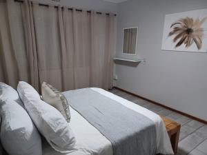 金伯利11 Debonair Self Catering Apartment的卧室里有一张床，床单和枕头都是白色的