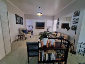 金伯利11 Debonair Self Catering Apartment的客厅里有一张沙发和一张摆满书籍的桌子