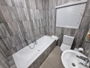 金伯利11 Debonair Self Catering Apartment的带浴缸、马桶和水槽的浴室