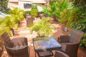 a patio with a table and chairs and palm trees at G-ONE HOTEL in Kampala