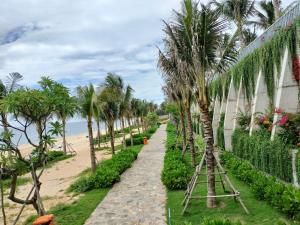 un chemin à côté d'une plage bordée de palmiers dans l'établissement Apec Mandala Wyndham Phan Thiet - Mui Ne, à Ấp Thiẹn Ái