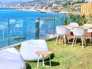 a table and chairs with a view of the water at Majestic Palm Beachfront Exotic Room in Batroun 