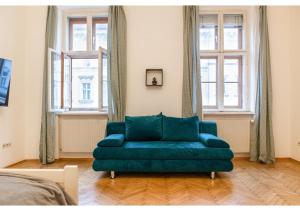 un sofá verde en una sala de estar con ventanas en Deluxe 3BR Apt. Wiener Stadthalle - Suitable for Longstays, en Viena
