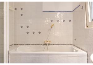 y baño de azulejos blancos con bañera blanca. en Deluxe 3BR Apt. Wiener Stadthalle - Suitable for Longstays, en Viena