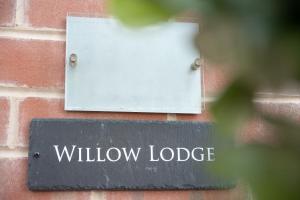a sign on the side of a brick wall with a window lodge at Willow Lodge Apartment in Solihull