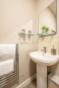uma casa de banho com lavatório, espelho e toalhas em Willow Lodge Apartment em Solihull