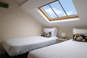 two beds in a attic room with a window at Central Llanrwst apartment ~ Perfect for walkers and MTB riders in Llanrwst