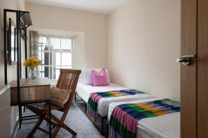 a bedroom with two beds and a chair and a window at Central Llanrwst apartment ~ Perfect for walkers and MTB riders in Llanrwst