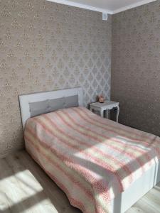 a bedroom with a bed with a red and white blanket at VILLA ROZA Guest House in Rēzekne