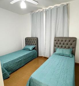 two beds sitting in a room with a window at Ap401 Praia do morro in Guarapari