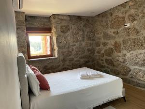 a bedroom with a white bed and a stone wall at Casa do capitão A casa ideal para férias no Gerês in Vieira do Minho +63 photos