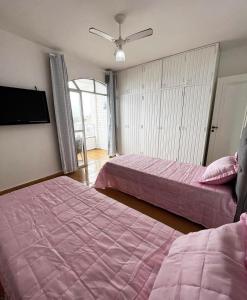 a bedroom with two beds and a flat screen tv at Ap401 Praia do morro in Guarapari