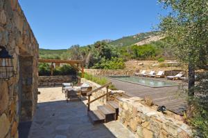 a patio with a pool and lounge chairs next to a building at Villa Bergeries De Calvi in Calvi