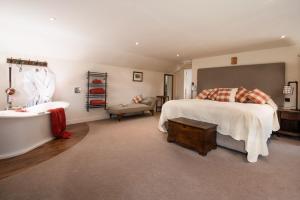 Anvil Cottage في Grewelthorpe: غرفة نوم بسرير كبير وحوض استحمام