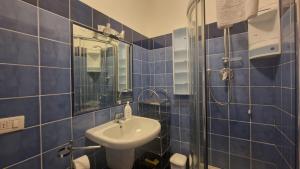uma casa de banho em azulejos azuis com um lavatório e um espelho em WH - Bussana em Sanremo