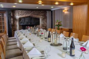 DoubleTree by Hilton Oxford Belfry في تايم: طاولة طويلة مع قماش الطاولة البيضاء وزجاجات النبيذ