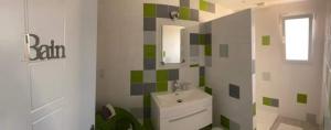 baño con lavabo y pared de azulejos verdes y blancos. en Chambre les Hortensias, en Challans