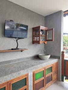 a bathroom with a sink and a tv on a wall at Dalem Arum (for women only) in Bandung