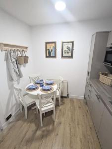 eine Küche mit einem weißen Tisch und Stühlen sowie einem Tisch und einer Küche in der Unterkunft The Cottage @ 59 in Colmonell