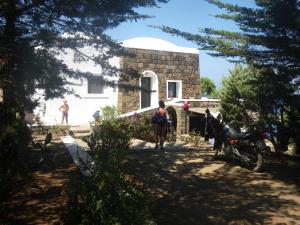 a woman walking a horse in front of a house at sull'arco dell'elefante in Pantelleria +2 photos