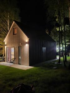 a small wooden building at night in a yard at Żywiołowo - domki w stylu stodoły z placem zabaw i stawem - OGIEŃ in Parchowo