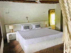 Un dormitorio con una cama blanca y una cruz en la pared en Casa Kalica, en Camacorinto