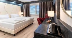 a bedroom with a bed and a desk with a mirror at PLAZA INN Wiener Neustadt, BW Signature Collection in Wiener Neustadt
