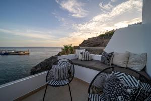 two chairs and a bench on a balcony overlooking the water at Casa Galana in Tías